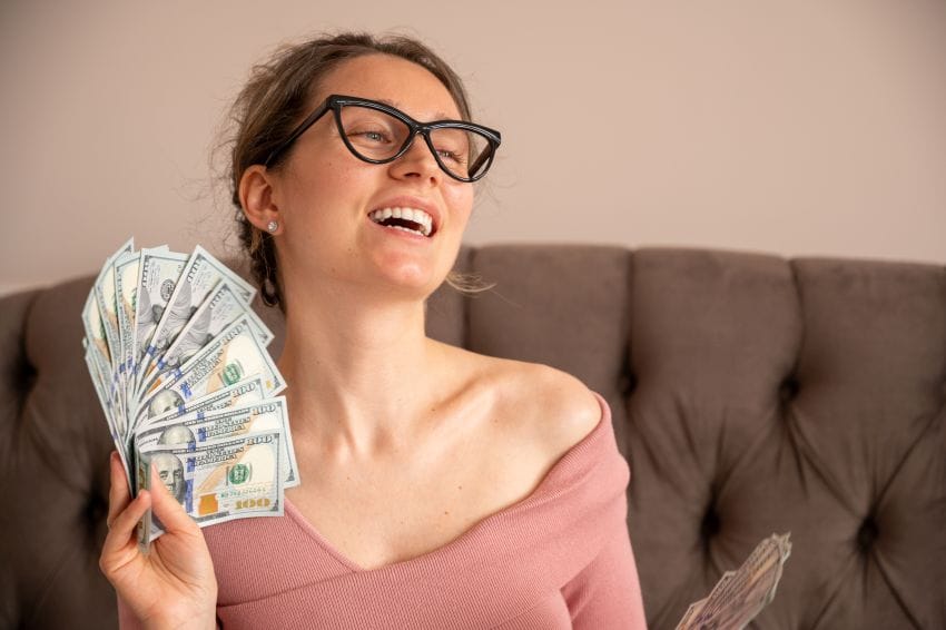 horoskop devojka drži novčanice i smeje se