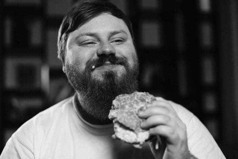 Nasmejani muškarac jede burger u tekstu o restoranu koji naplaćuje povraćanje gostiju
